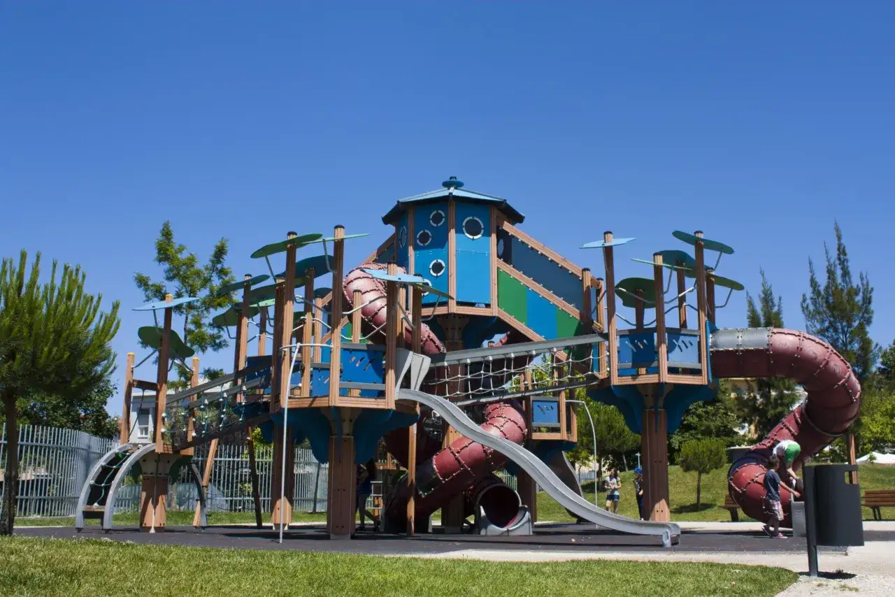 Parque infantil con toboganes curvos y estructuras de madera, ideal para oporto con niños.