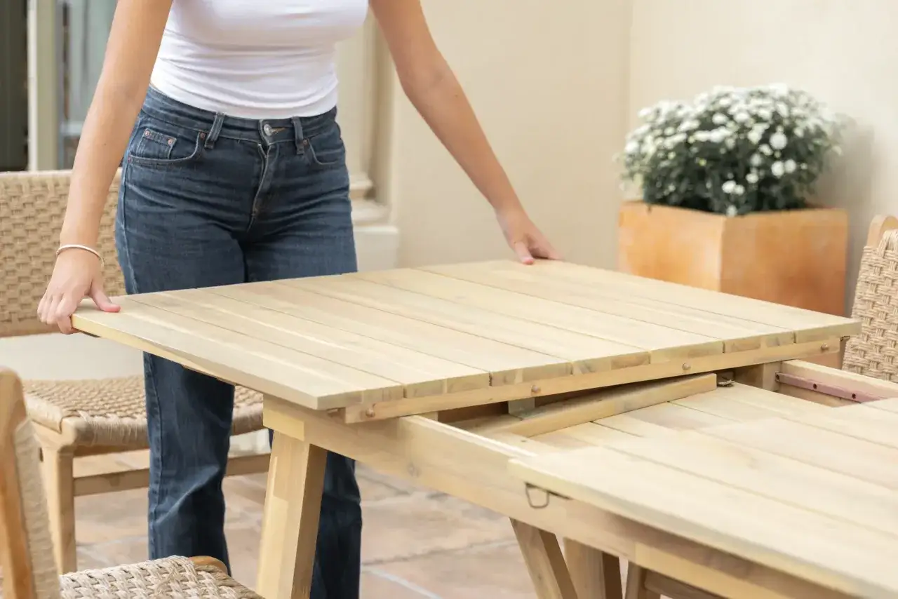 Persona extendiendo una mesa de madera, mostrando c&oacute;mo abrir una mesa extensible para m&aacute;s espacio.