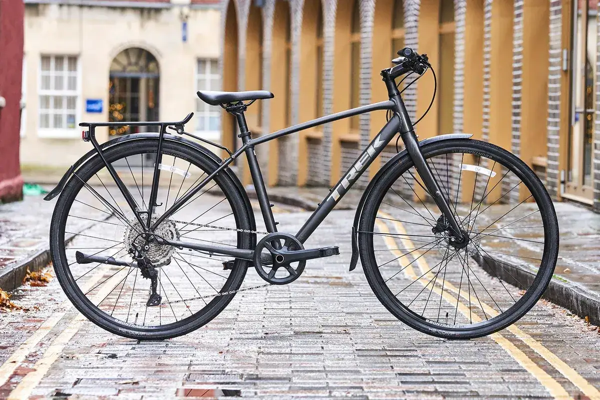 A Trek hybrid bike, perfect for city commutes and light trails, stands on a wet cobblestone street.