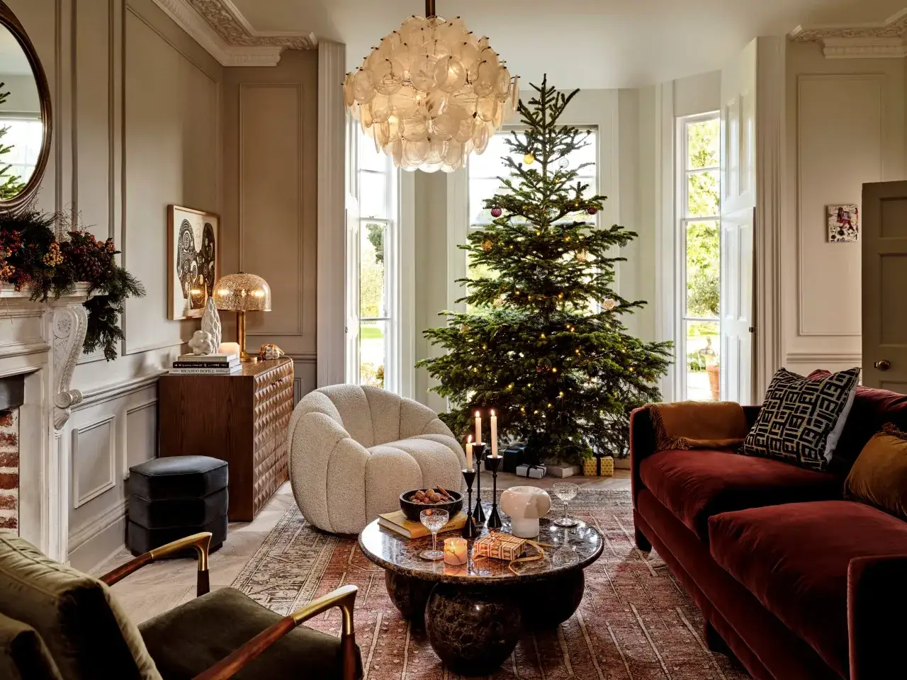 Ett vardagsrum redo f&ouml;r en mysig jul med julgran, levande ljus och presenter.