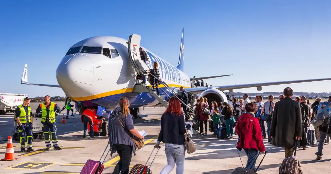 Pasażerowie z walizkami idą na boarding do samolotu Ryanair.