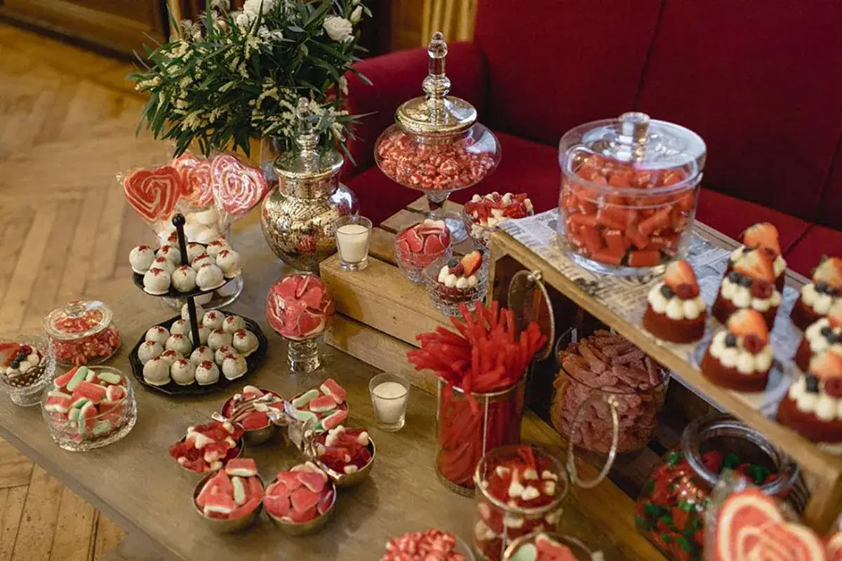 Un candy bar boda casero lleno de dulces rojos y rosas, piruletas, pasteles y gomitas.