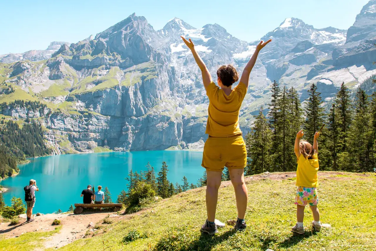 Familia disfrutando de un día en la suiza con niños, con un lago turquesa y montañas imponentes de fondo.