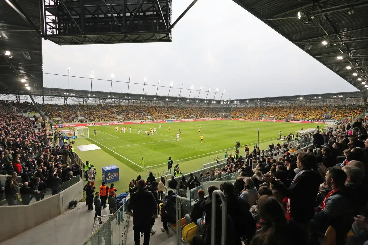 Widownia na stadionie podczas meczu GKS Katowice – Górnik Zabrze. Piłkarze na murawie, trybuny wypełnione kibicami w żółtych barwach.