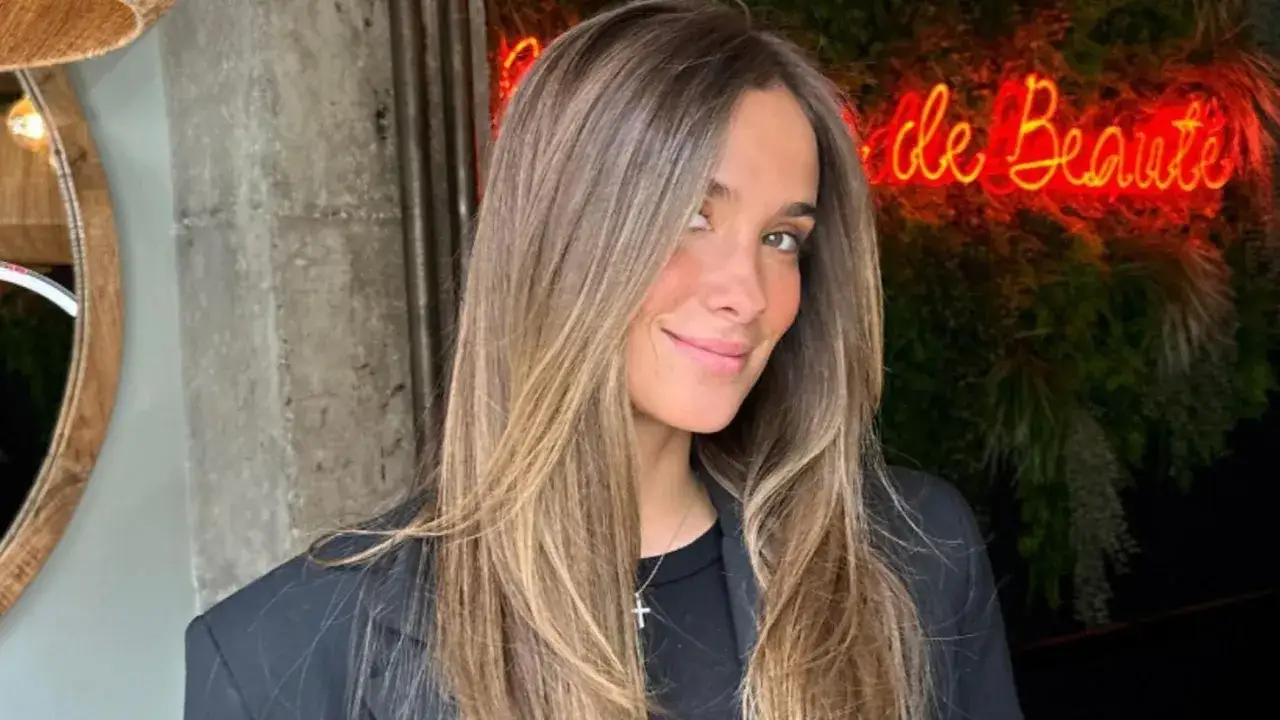 María Pombo, con su melena castaña y un blazer negro, sonríe ante un letrero de neón que dice