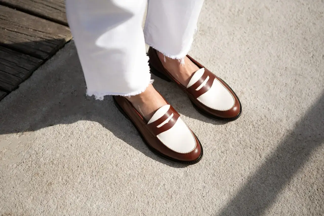 Une tenue chic avec un pantalon blanc évasé et des mocassins femme bicolores marron et blanc, parfaits pour un look printanier.