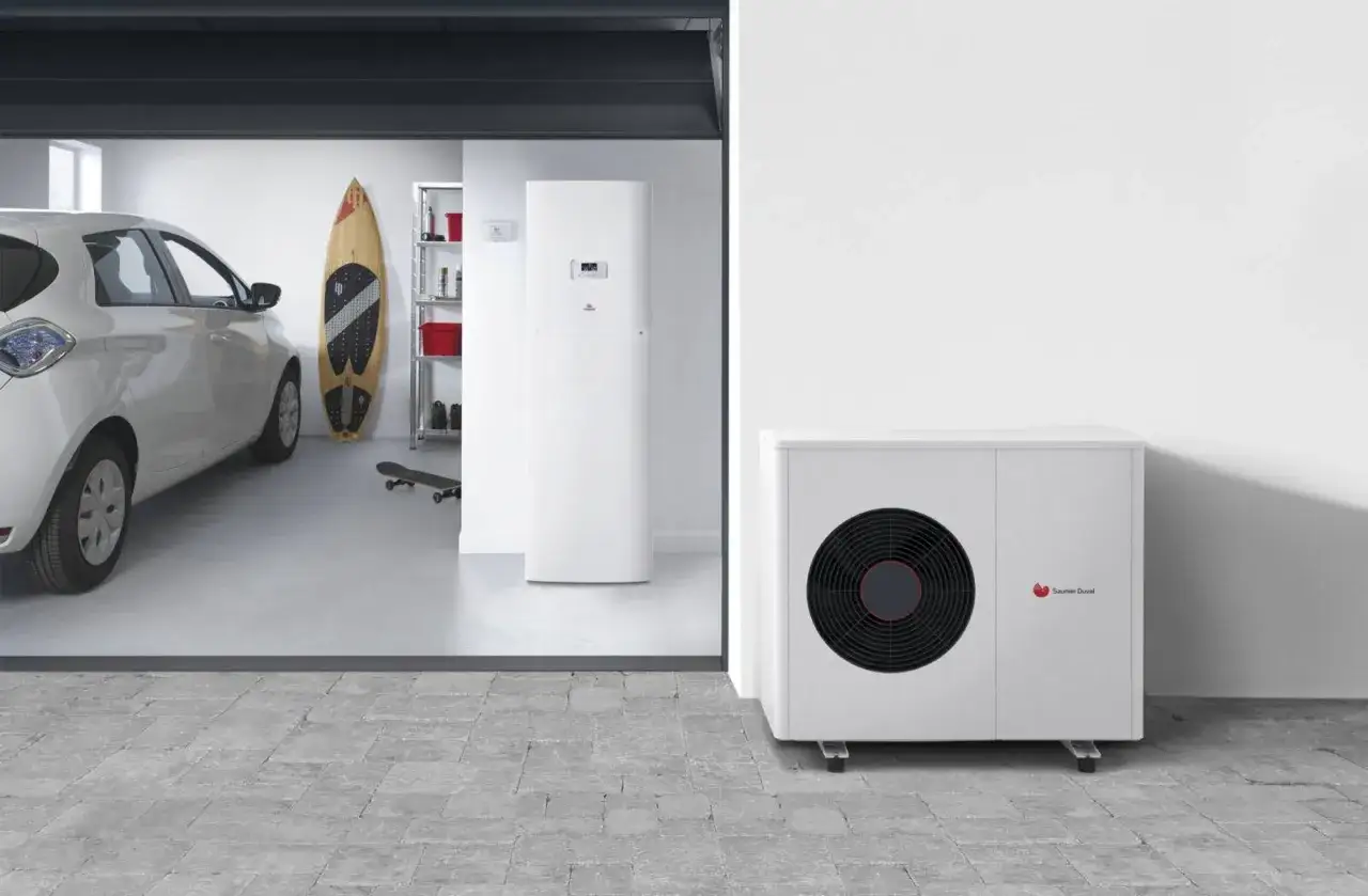 Un problème avec la pompe à chaleur Saunier Duval ? L'unité extérieure est visible à côté d'une voiture électrique dans un garage.