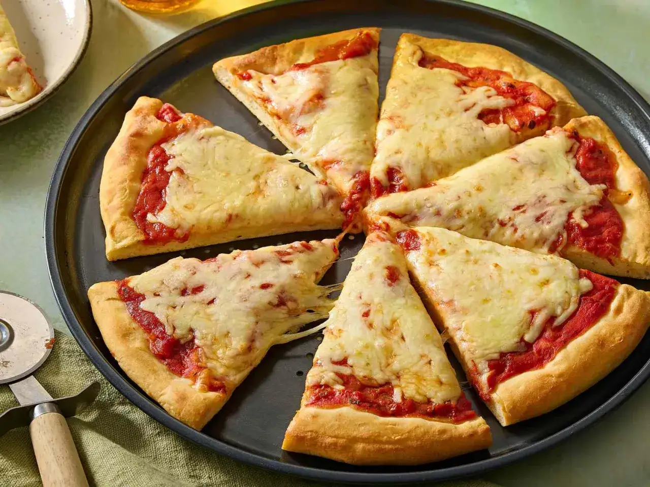 En hel pizza med tomatsås och smält ost, skuren i bitar. Ett perfekt pizza recept för hemmabruk.