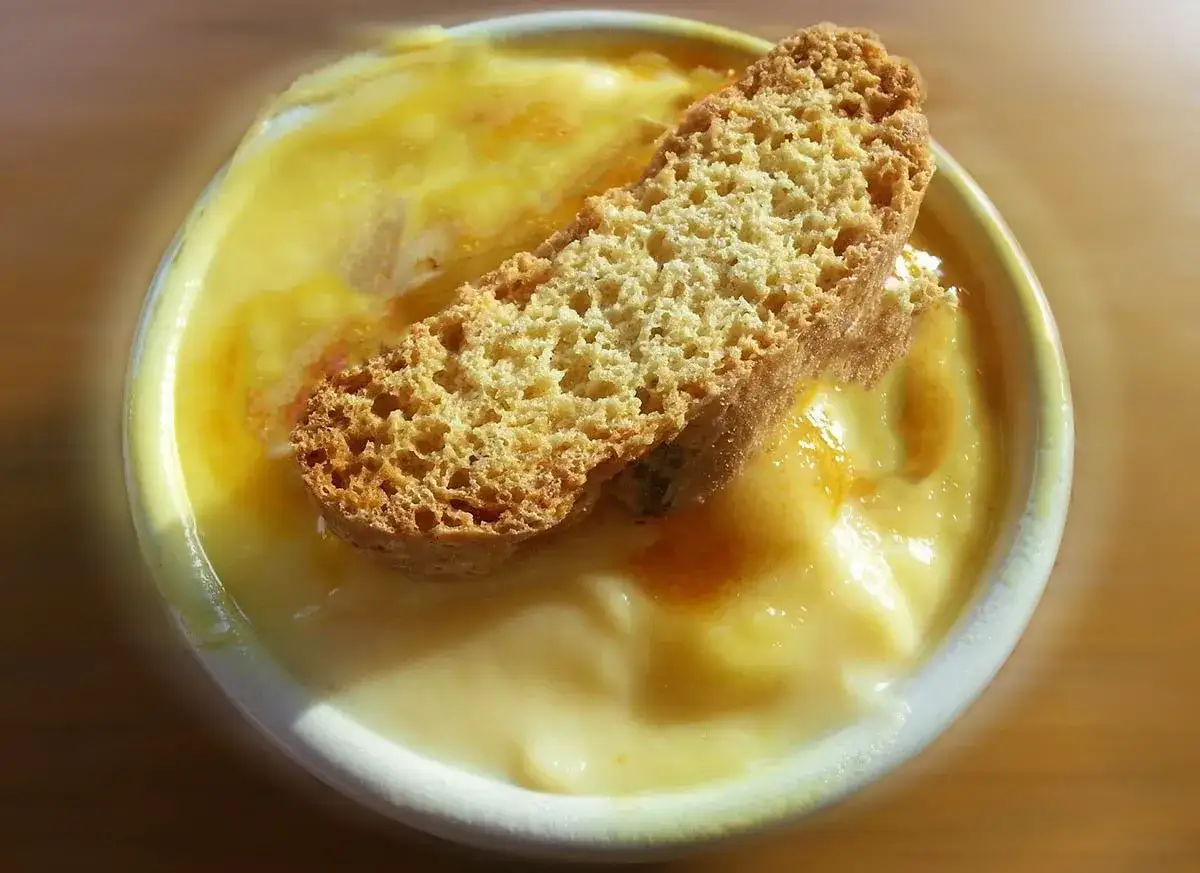Budino di semolino fatto in casa da Benedetta, cremoso e dorato, con una fetta di biscotto croccante adagiata sopra.