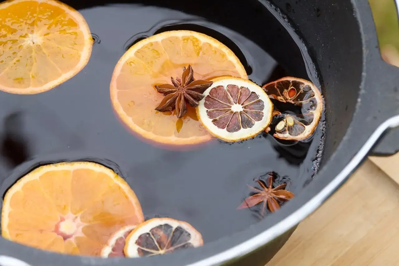 Tranches d'orange et d'orange s&eacute;ch&eacute;e, avec des &eacute;toiles de badiane, flottant dans un liquide sombre, pr&ecirc;tes pour une recette de vin chaud.