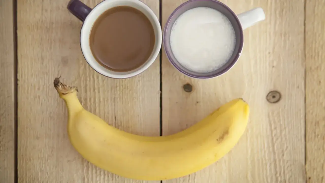 Uśmiechnięta buźka ze szklanki kawy, mleka i banana. Idealny banan na pusty żołądek na śniadanie.