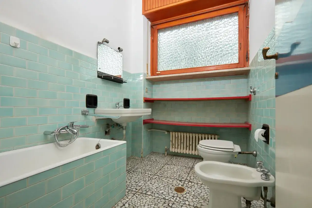 Alt-Text: Ein veraltetes Badezimmer mit türkisfarbenen Kacheln und einem Bidet. Hier stellt sich die Frage, wann muss Vermieter Bad renovieren?