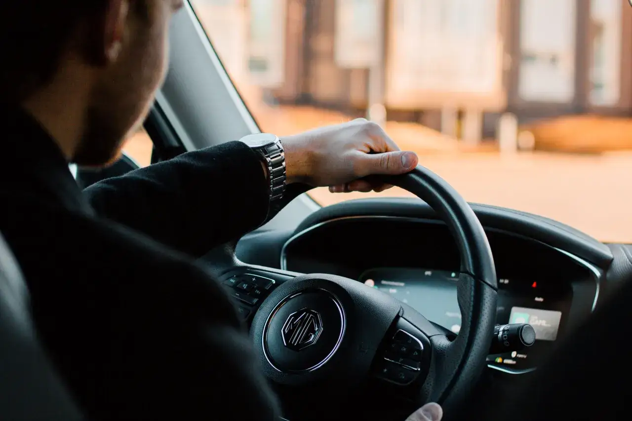 F&ouml;rarens hand p&aring; ratten i en bil. T&auml;nk p&aring; vad som ing&aring;r i leasing av bil n&auml;r du k&ouml;r.