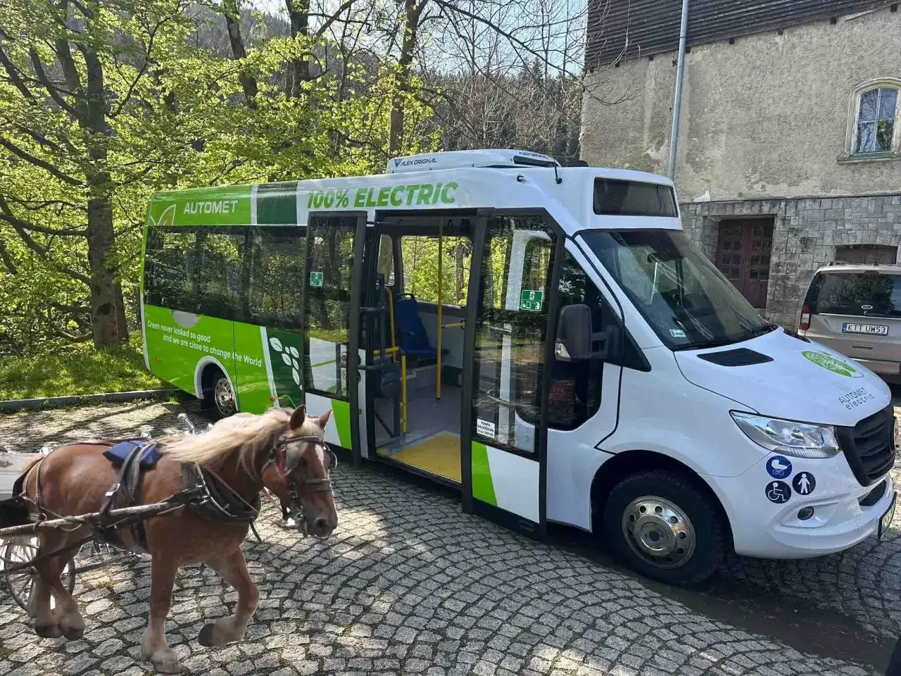 Koń zaprzężony do wozu obok elektrycznego autobusu 