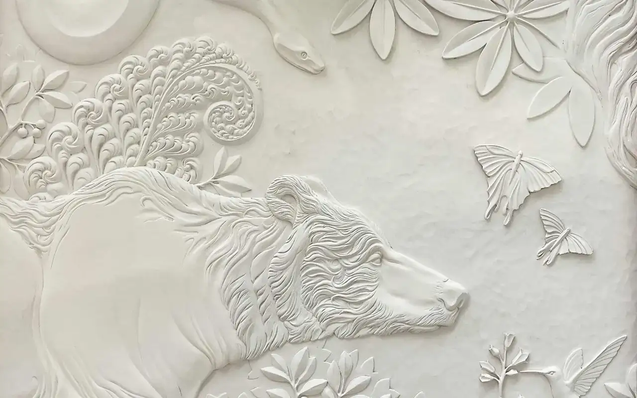 Biały, misterny relief wklęsły przedstawia niedźwiedzia, węża i motyle wśr&oacute;d liści.