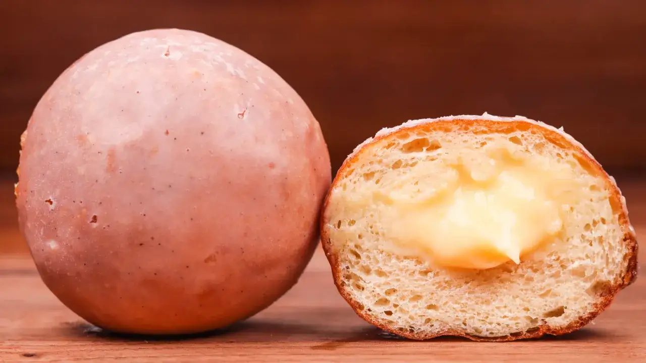 Ein ganzer und ein aufgeschnittener Krapfen mit cremiger Füllung. Perfekt für Ihr nächstes Donuts Rezept!