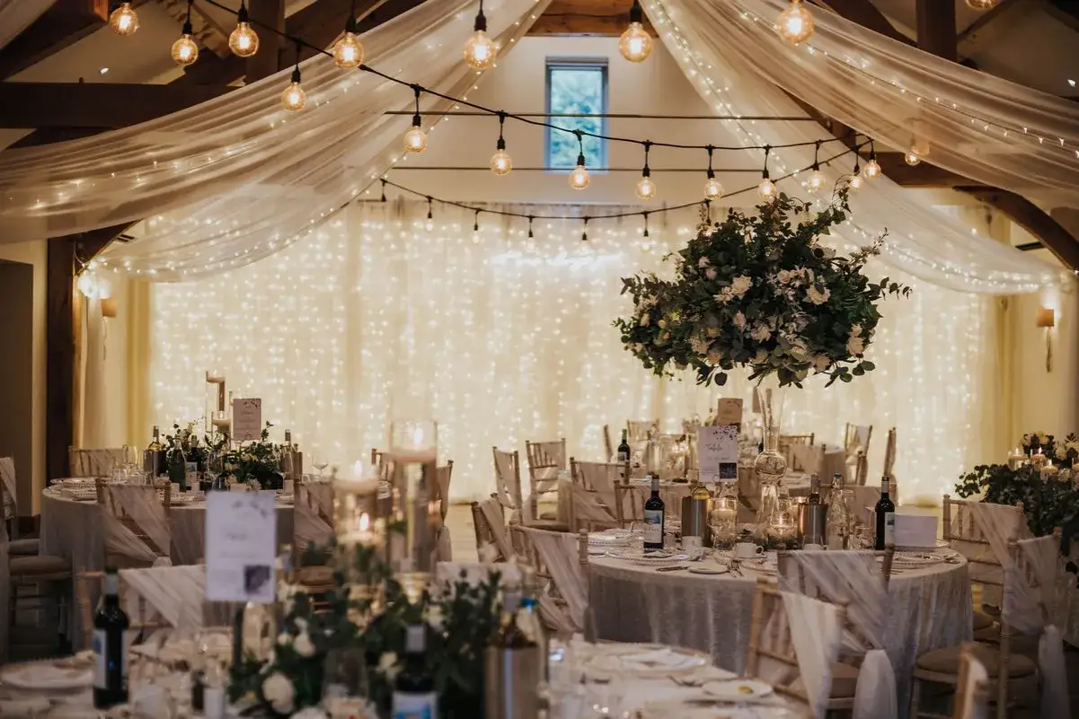 Elegancka sala weselna z girlandami światełek i kwiatami. Nawet tani ślub może wyglądać magicznie!