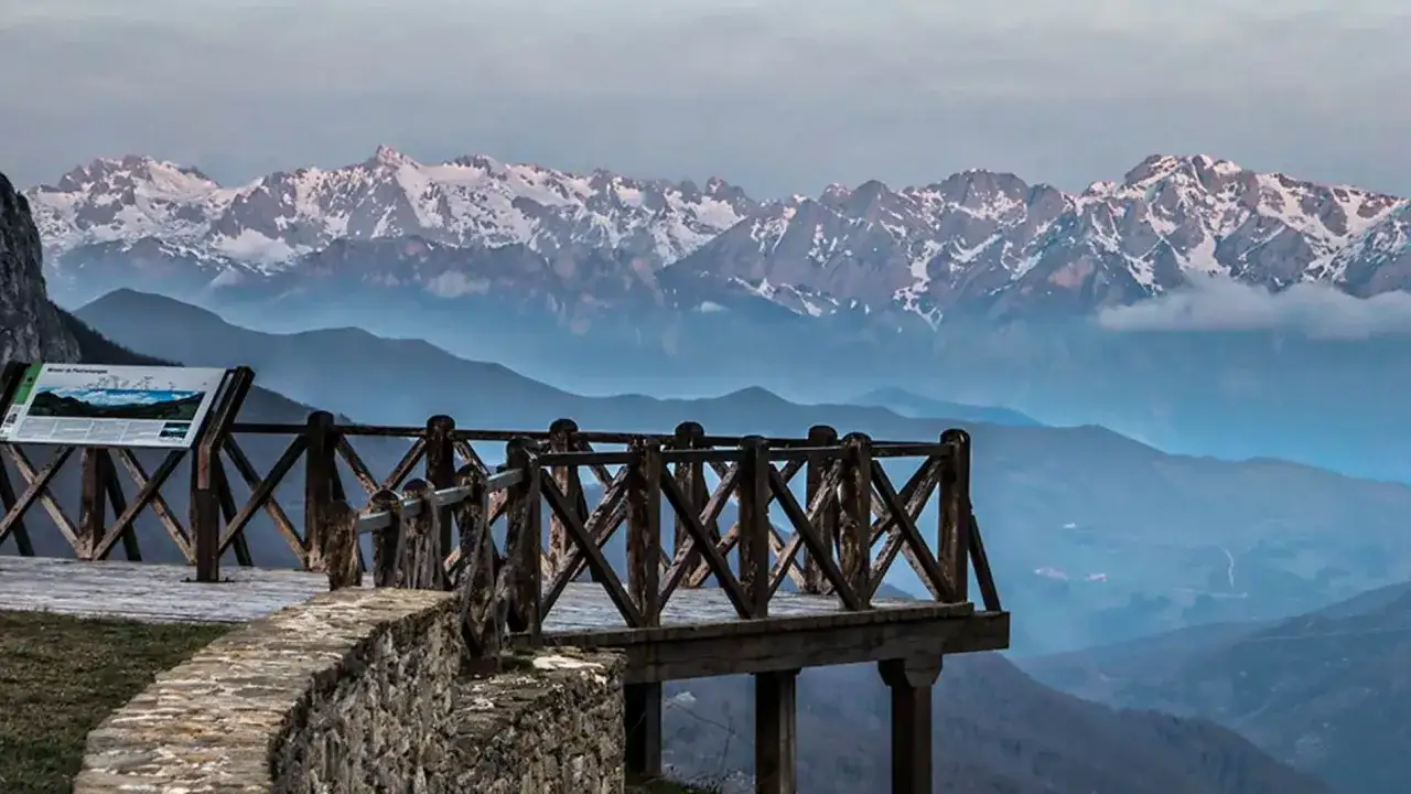 Mirador con barandilla de madera para ver Picos de Europa nevados.