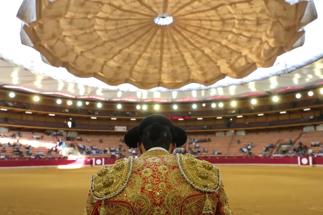 Torero de espaldas, bajo la c&uacute;pula de la plaza de toros de Zaragoza, con los asientos llenos de p&uacute;blico.
