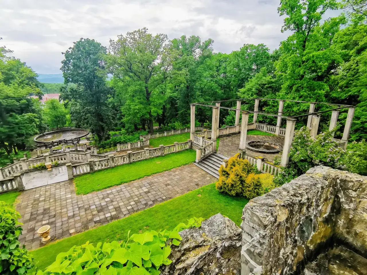 Ogród przy pałacu Marianny Orańskiej z kamiennymi balustradami, schodami i pergolą.