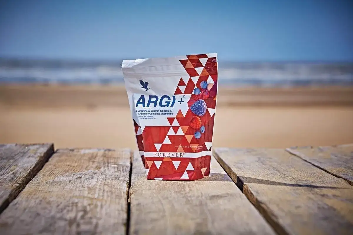Opakowanie suplementu argi+ z jagodami na tle plaży. Idealne na wakacje!
