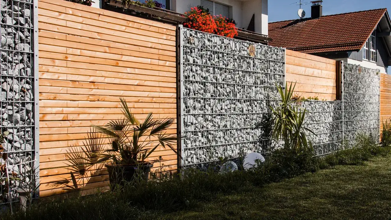 Moderne gartenzaun ideen bilder: Holzelemente wechseln sich mit Gabionen ab, um einen stilvollen und robusten Zaun zu schaffen.