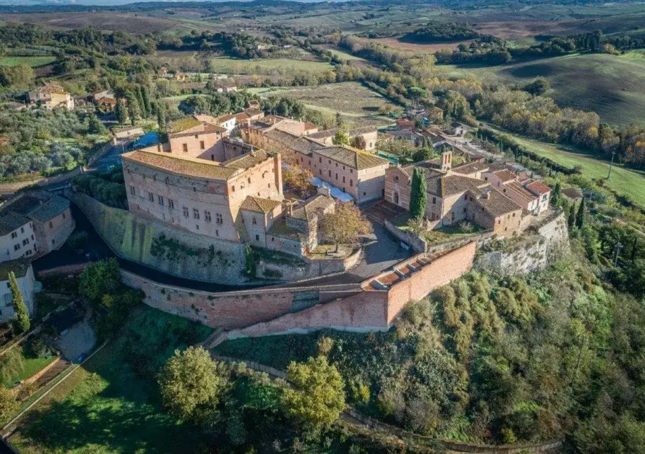 Borgo fortificato di San Giovanni d'Asso, con il suo imponente castello e le case in pietra, domina le dolci colline toscane.
