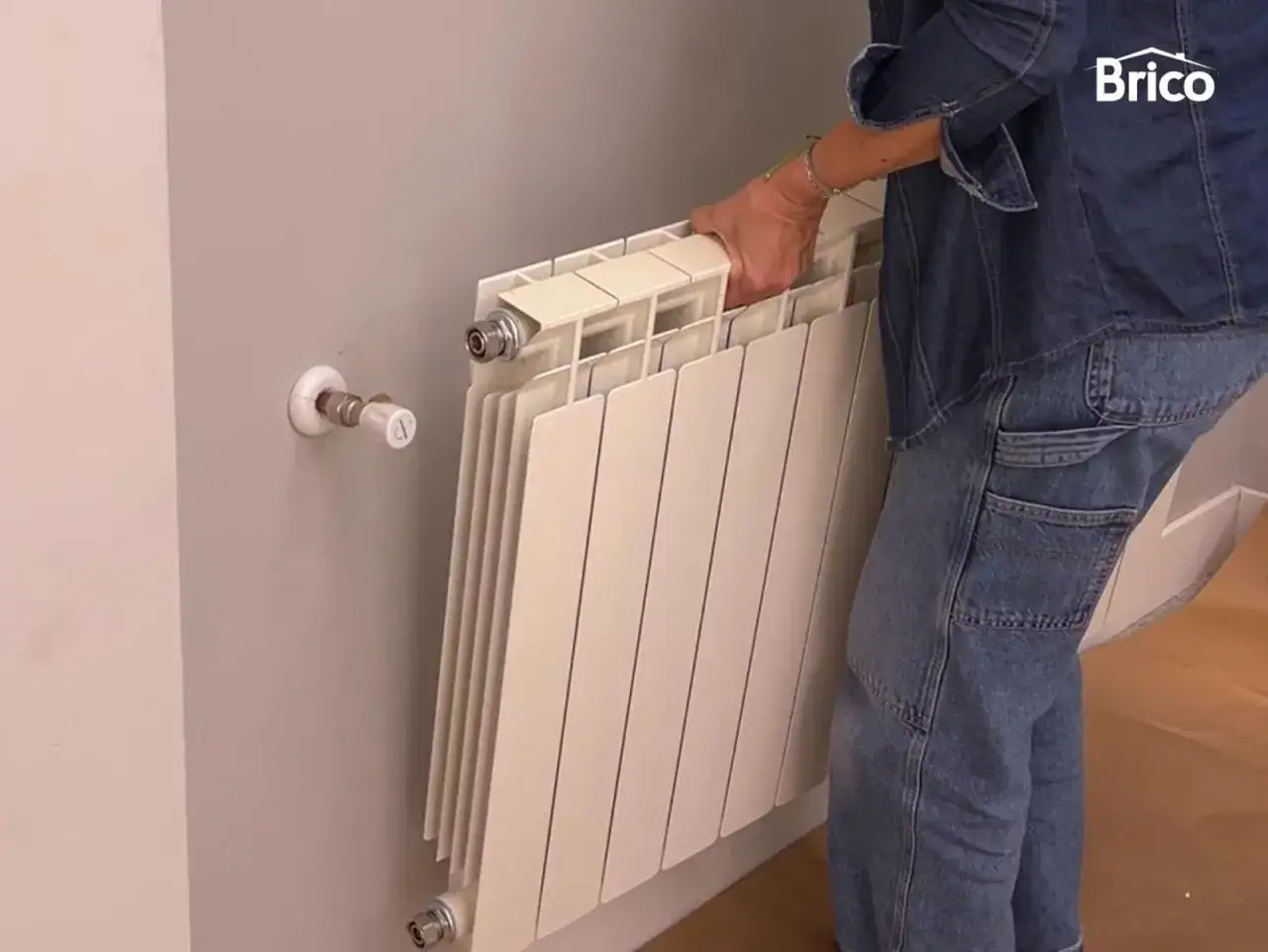 Persona quitando radiadores para pintar la pared.