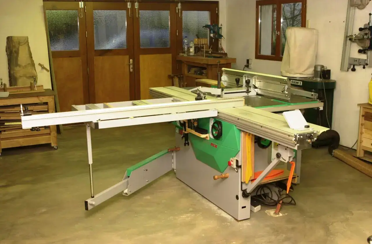 Un atelier de menuiserie avec une scie circulaire Felder KF700, des outils et des portes en bois.