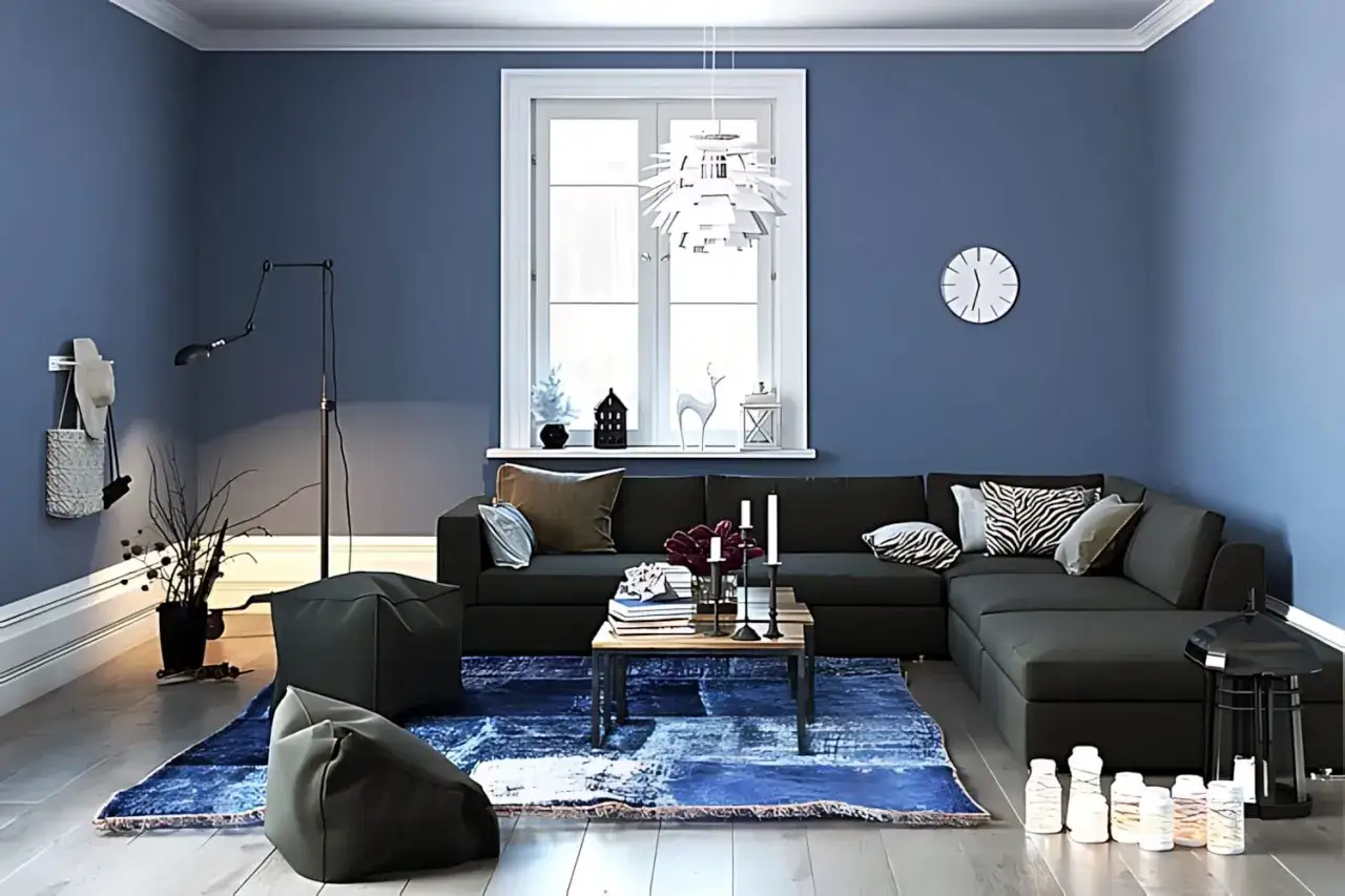 Gem&uuml;tliches Wohnzimmer mit dunklem Sofa, blauer Teppich und Kissen. Ein Hocker aus Vlies steht im Vordergrund.