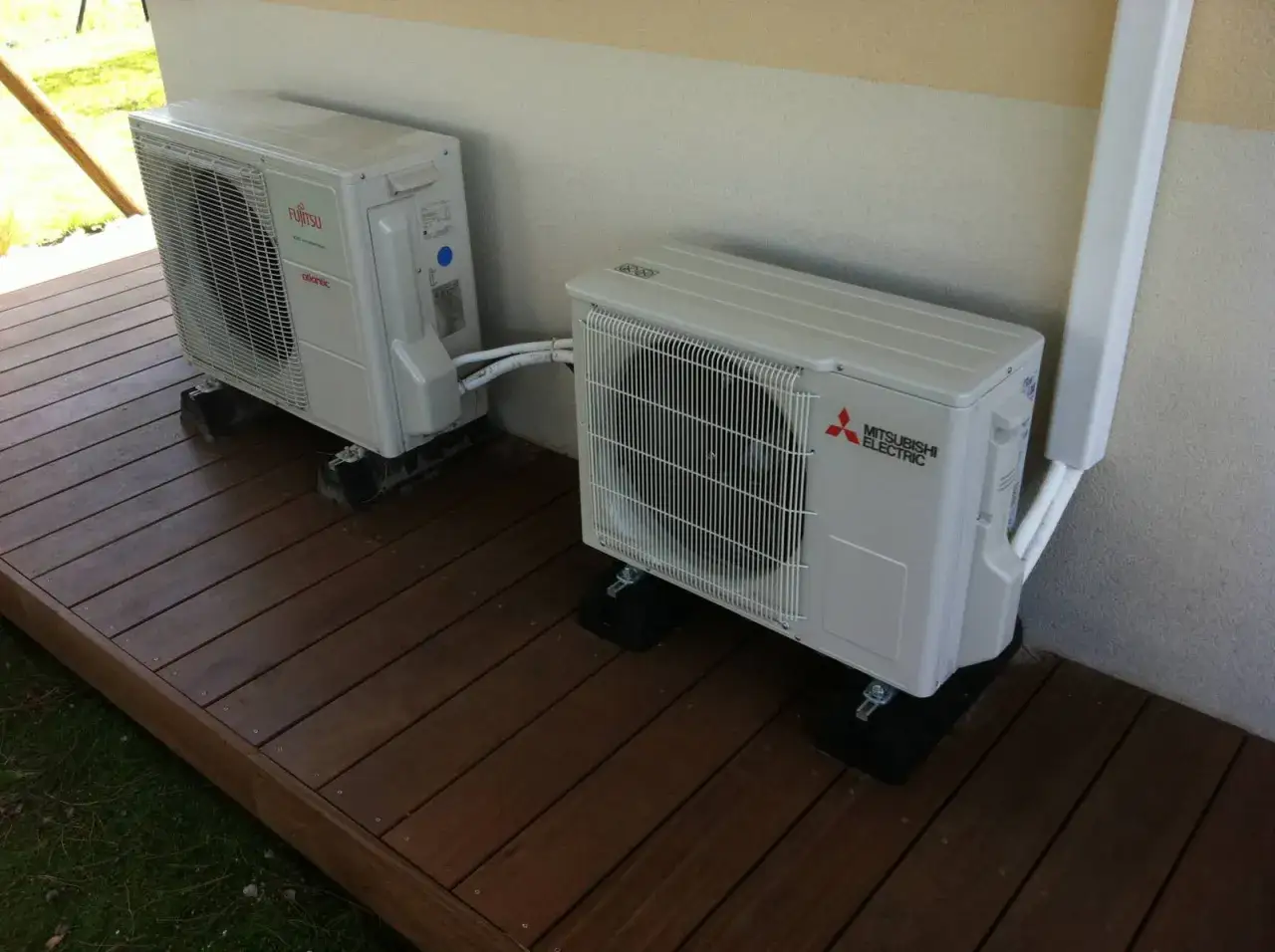 Deux unités extérieures de climatisation, dont une Mitsubishi Heavy Industries, sont installées sur une terrasse en bois.