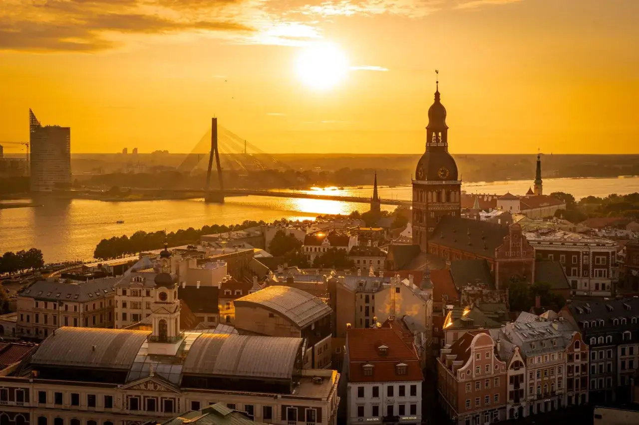 Zachód słońca nad Rygą. Zobaczysz tu katedrę, most i nowoczesne budynki.