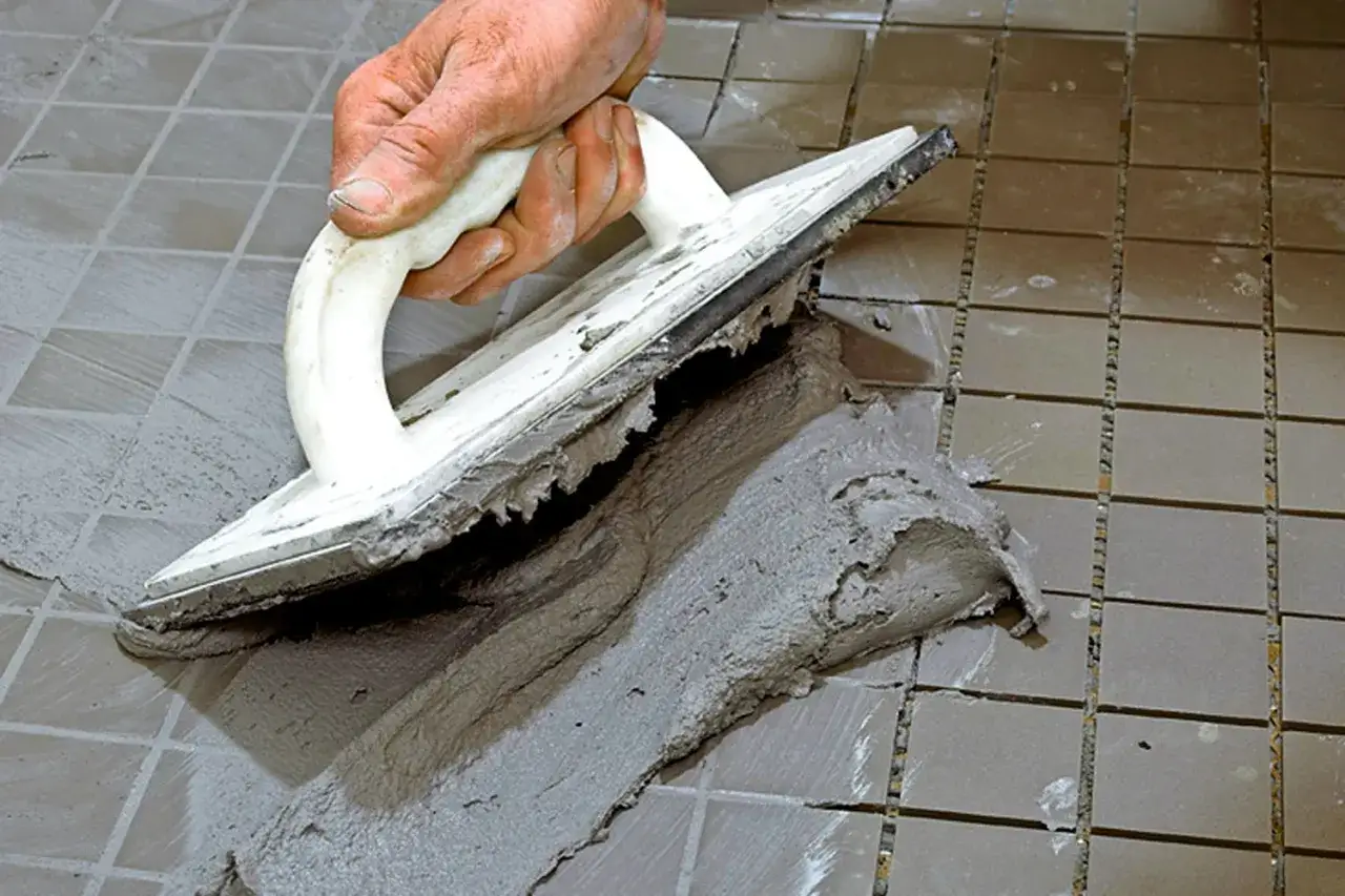 Hand spreading cement with a trowel to foga om kakel.