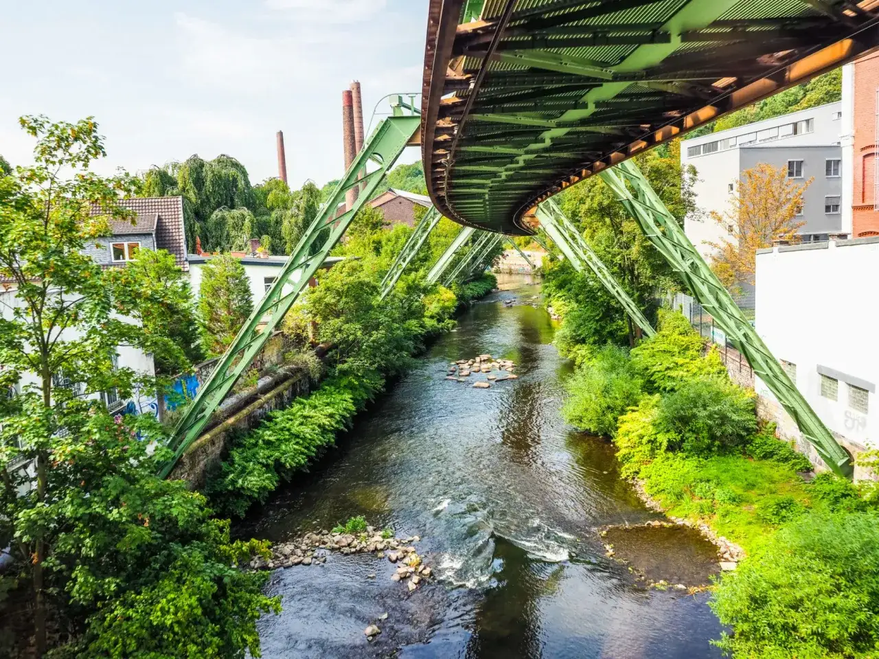 Schwebende Bahn über Fluss, grüne Ufer und alte Fabrikschlote. Ein toller Fotospot in NRW für einzigartige Perspektiven.