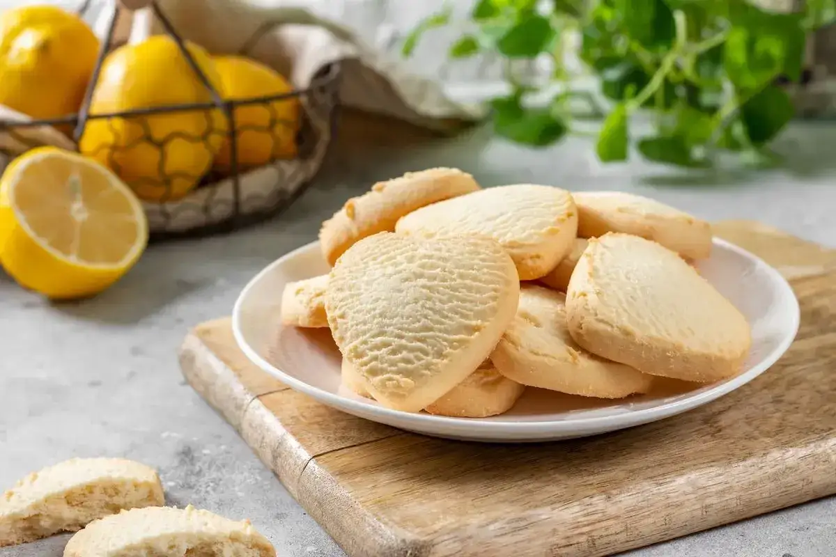 Deliziosi biscotti senza burro, dorati e profumati, con limoni freschi sullo sfondo.