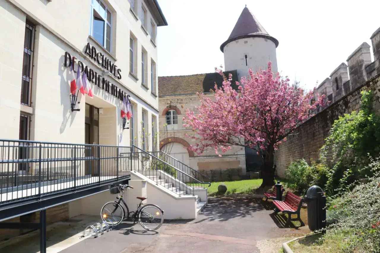 Devant les Archives D&eacute;partementales de l'Yonne, un cerisier en fleurs c&ocirc;toie une tour m&eacute;di&eacute;vale.