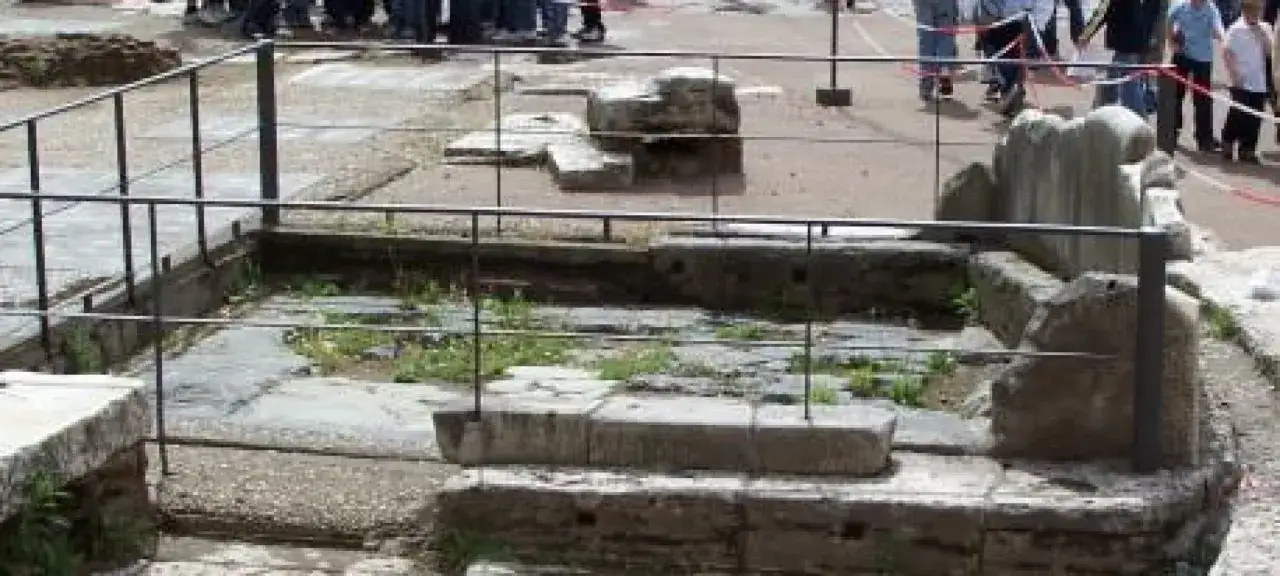 Resti archeologici del Lapis Niger, un'area sacra nel Foro Romano, protetta da una recinzione.