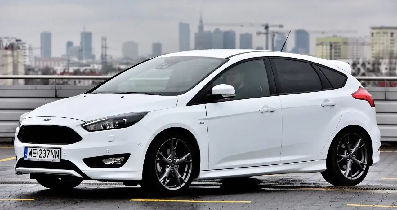Biały Ford Focus na parkingu, z widokiem na miasto w tle. Idealny do sprawdzenia ford focus dane techniczne.