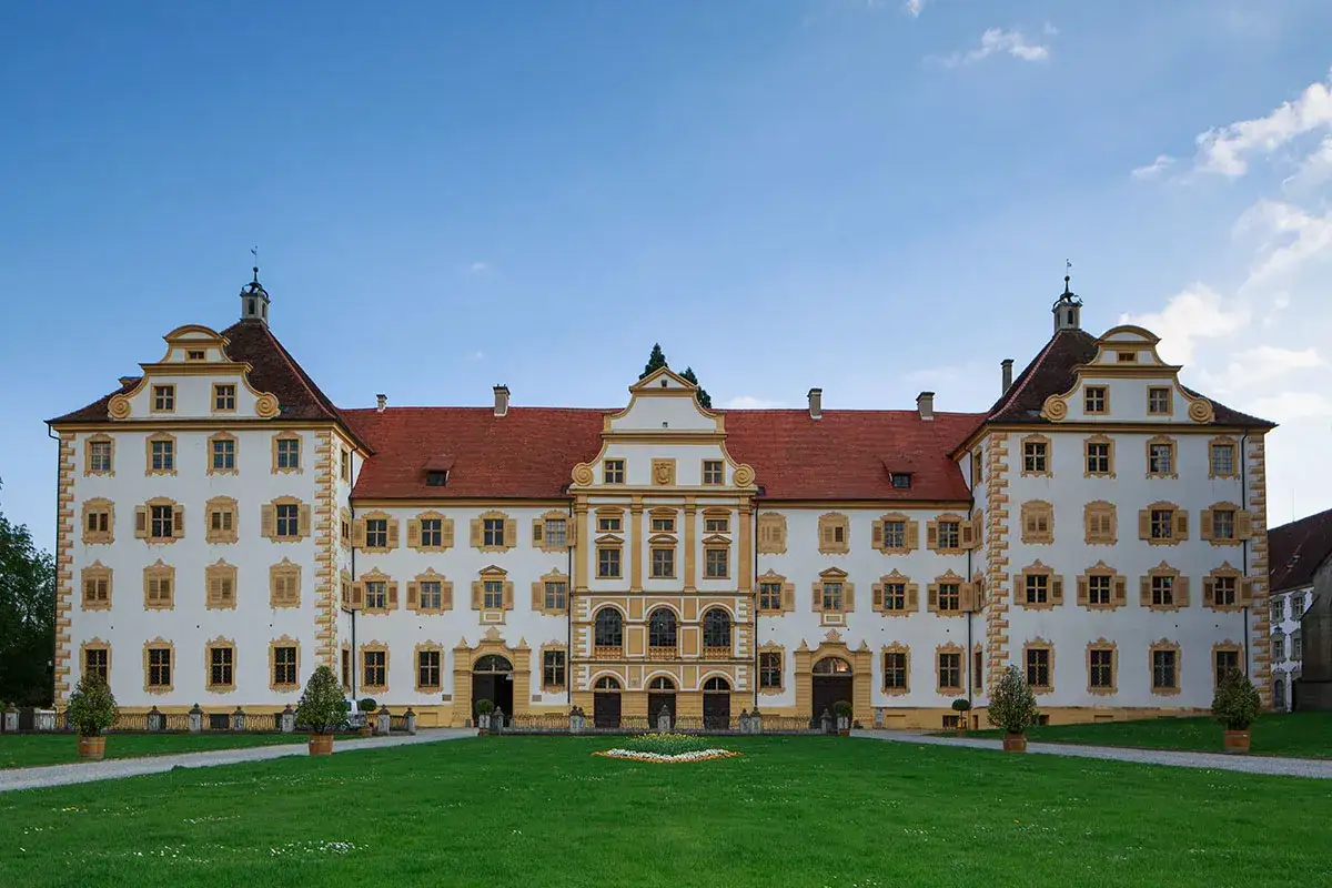 Das Schloss Salem erstrahlt in wei&szlig;er Pracht mit roten D&auml;chern vor blauem Himmel. Ein gepflegter Rasen l&auml;dt zum Verweilen ein.