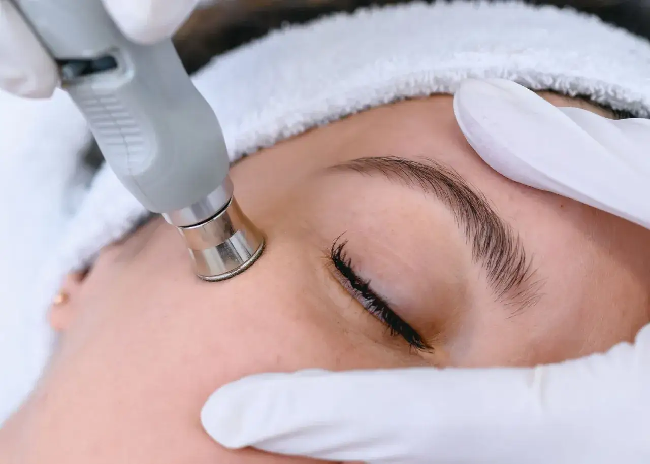 Trattamento viso con manipolo per migliorare l'elasticit&agrave; della pelle. Mani guantate e fascia per capelli.
