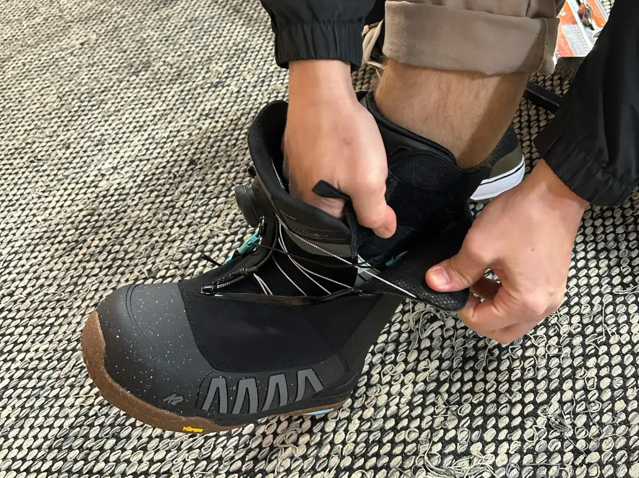Dłoń zapina but snowboardowy. Szerokość deski snowboardowej jest kluczowa dla dopasowania buta.