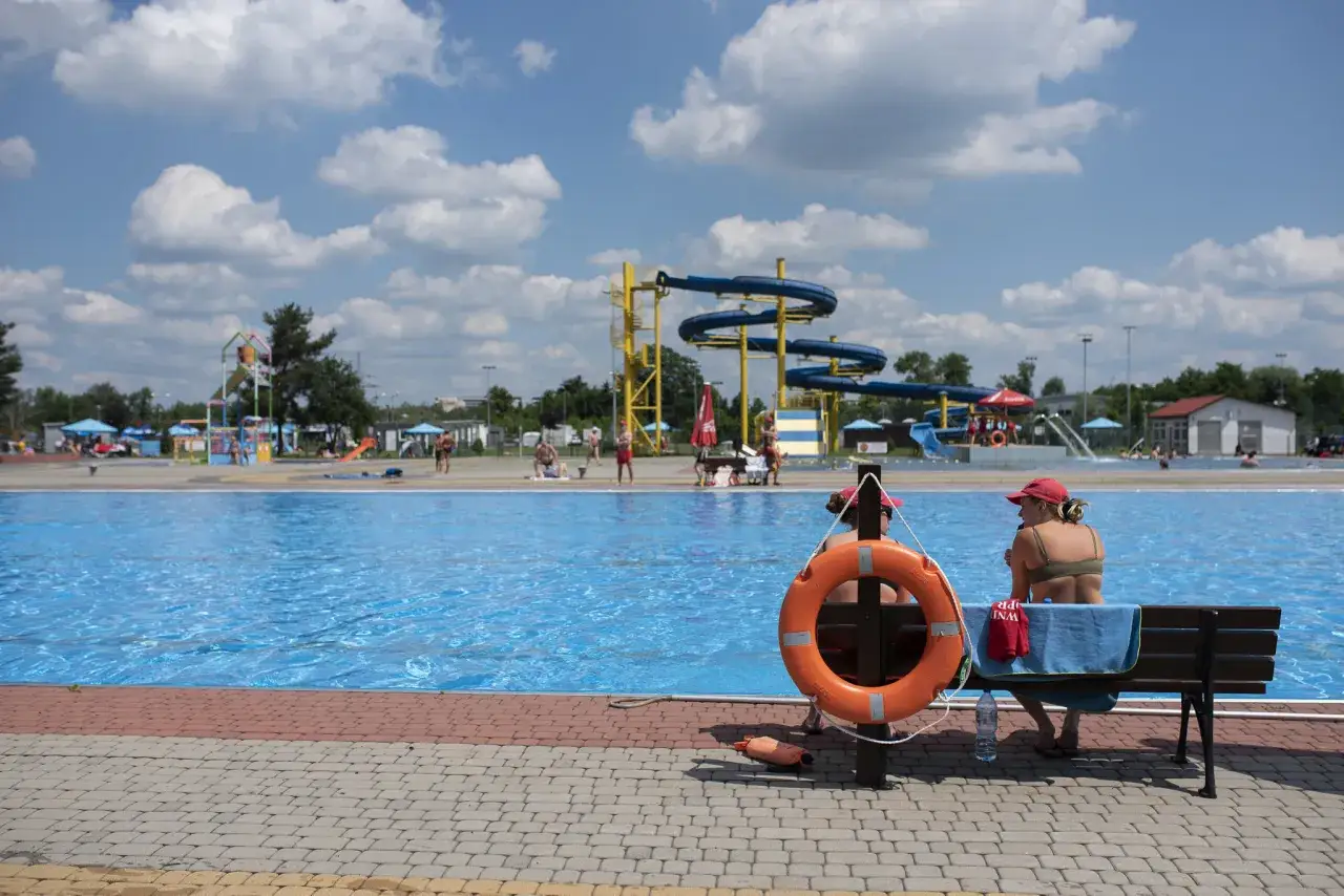 Letni dzień w parku wodnym. Woda w basenie lśni, a w tle widać zjeżdżalnie. Idealne miejsce na wykorzystanie bonu turystycznego.