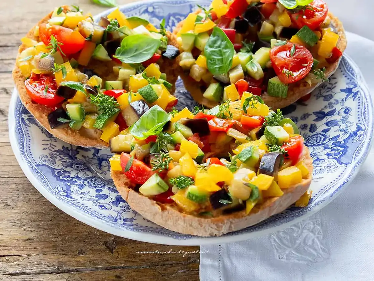 Friselle condite con verdure miste colorate: pomodorini, zucchine, peperoni e melanzane. Un'idea gustosa su come condirle.