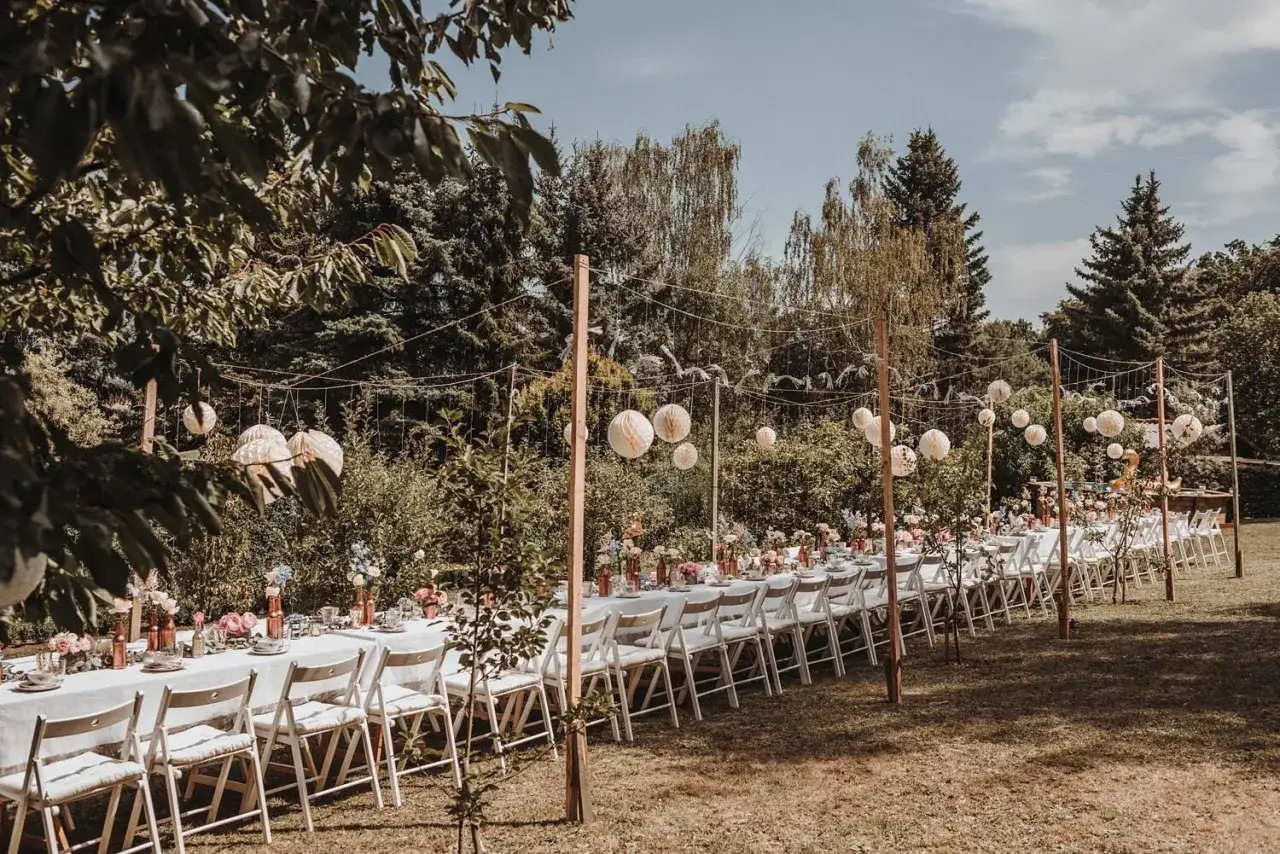 Festlich gedeckte Tafel für eine Garten Hochzeit, geschmückt mit Blumen und Papierlaternen.