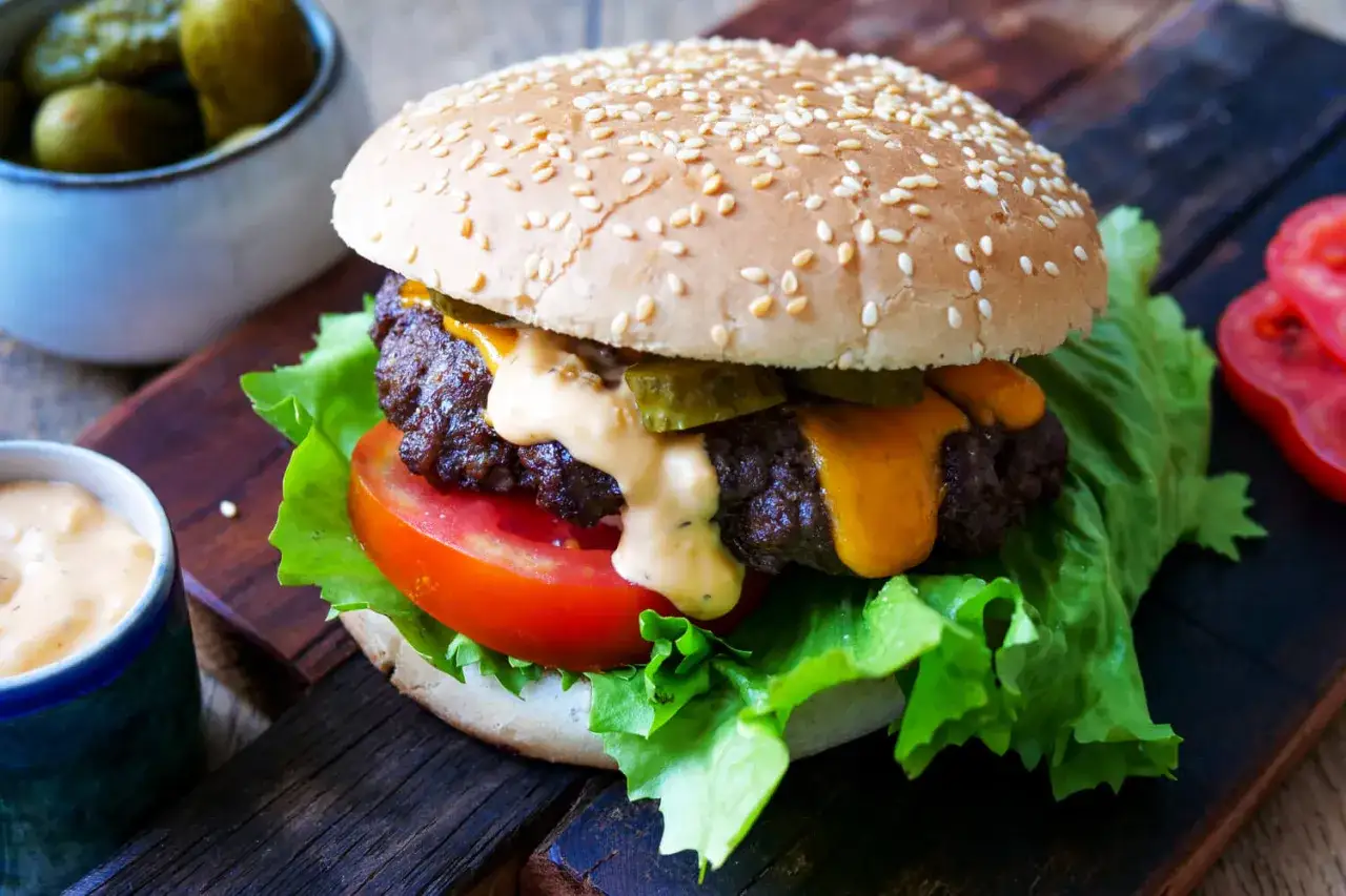 Saftiger Burger im Airfryer zubereitet, mit Käse, Gurken und Sauce auf knackigem Salat.