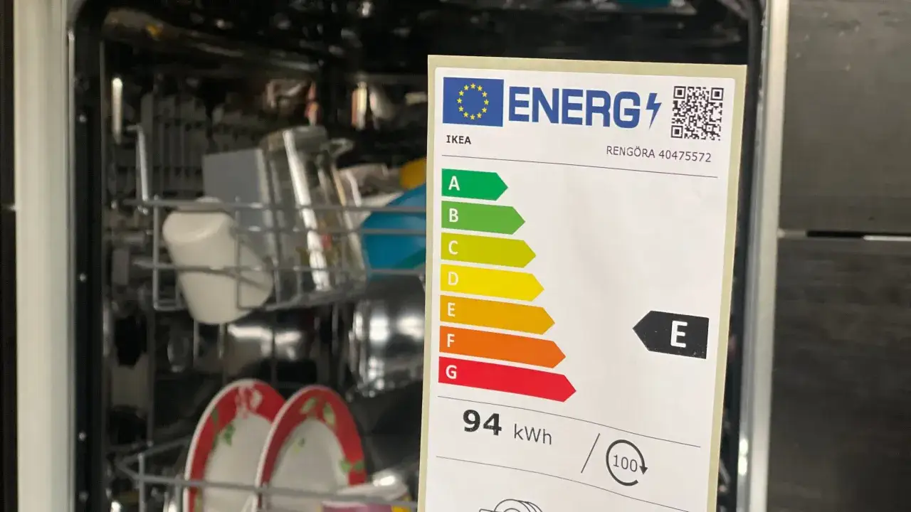 Etykieta energetyczna zmywarki IKEA RENGÖRA, klasa E, zużycie 94 kWh. Wnętrze zmywarki pełne naczyń.
