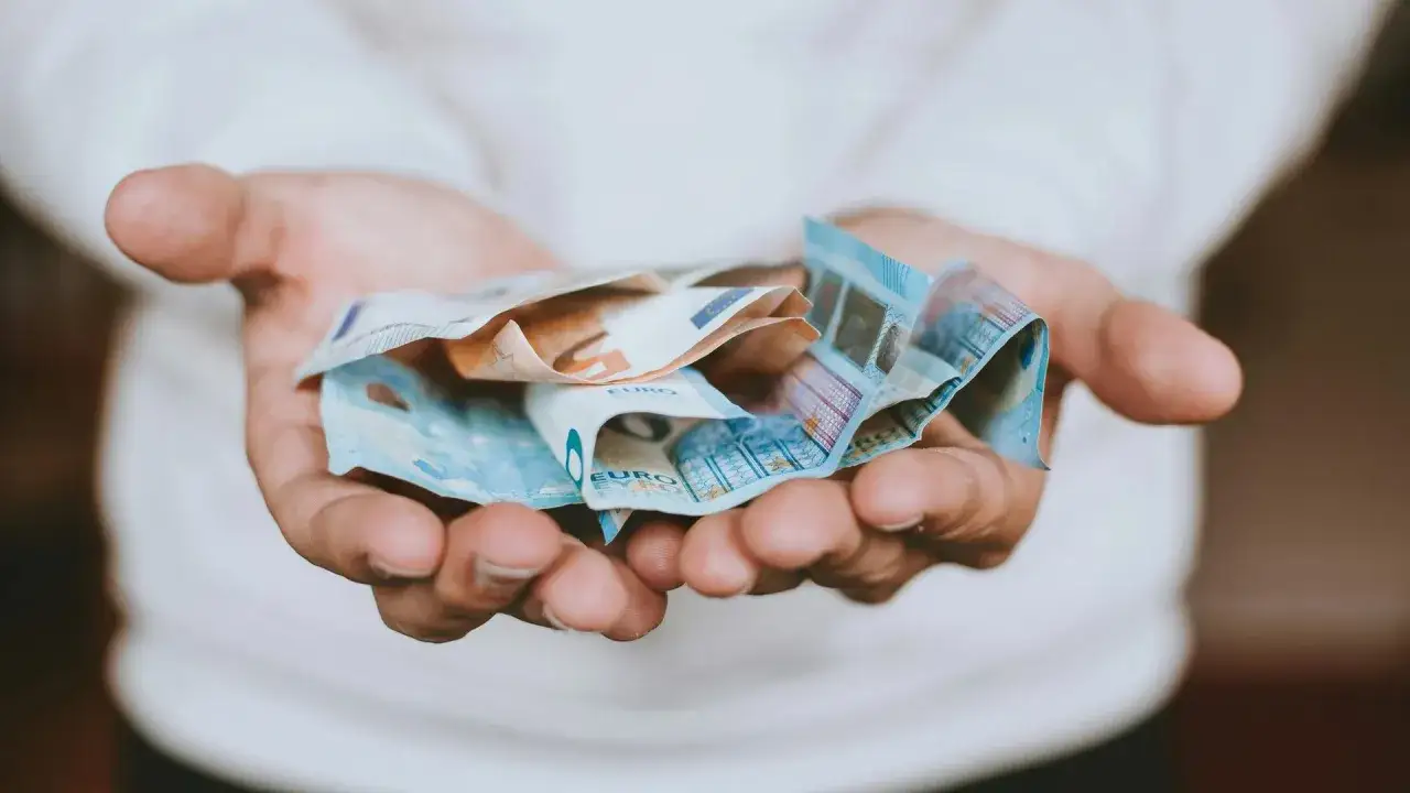 Dłonie trzymające banknoty euro, popularną walutę w Grecji.