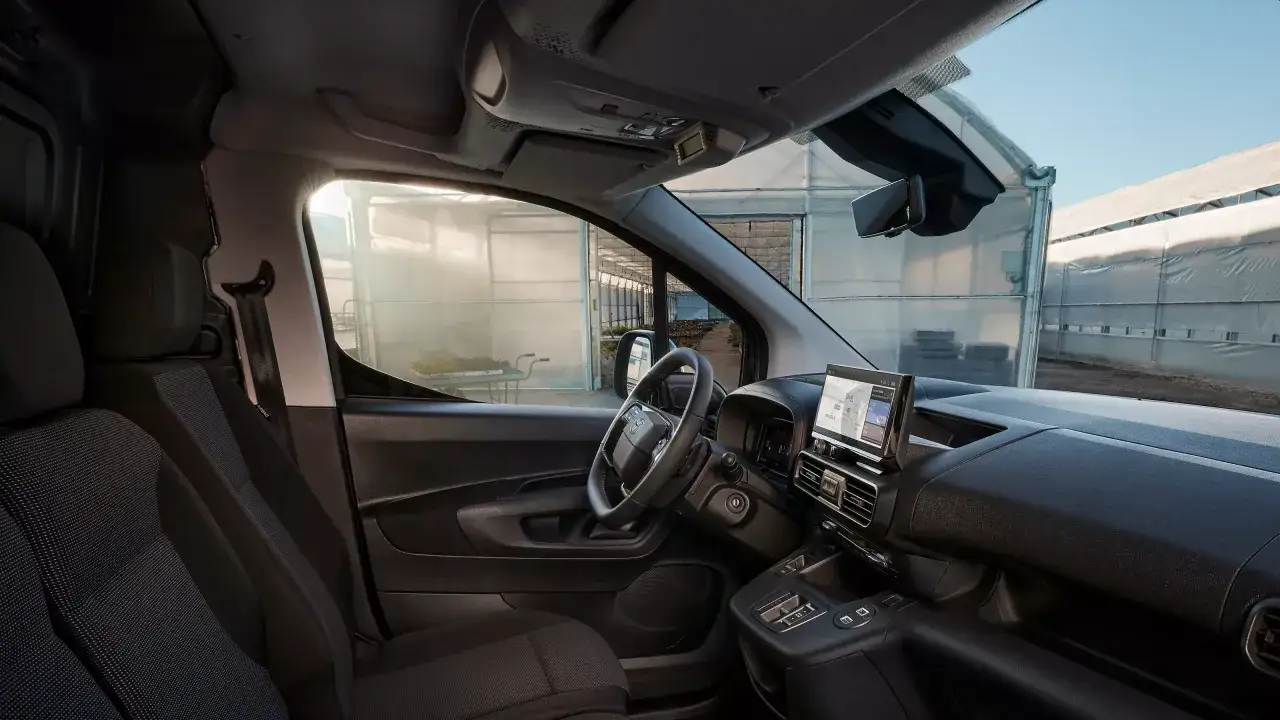Wnętrze Toyoty Proace z widokiem na szklarnię. Widoczne fotele, kierownica i ekran multimedialny.