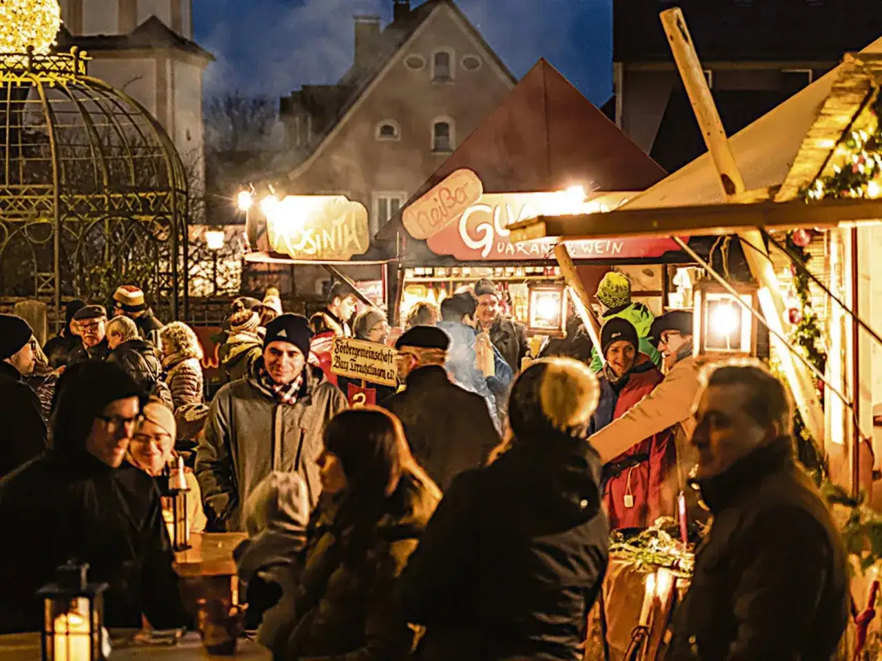 Menschen genießen die stimmungsvolle Treuchtlinger Schlossweihnacht mit Glühwein und Buden.