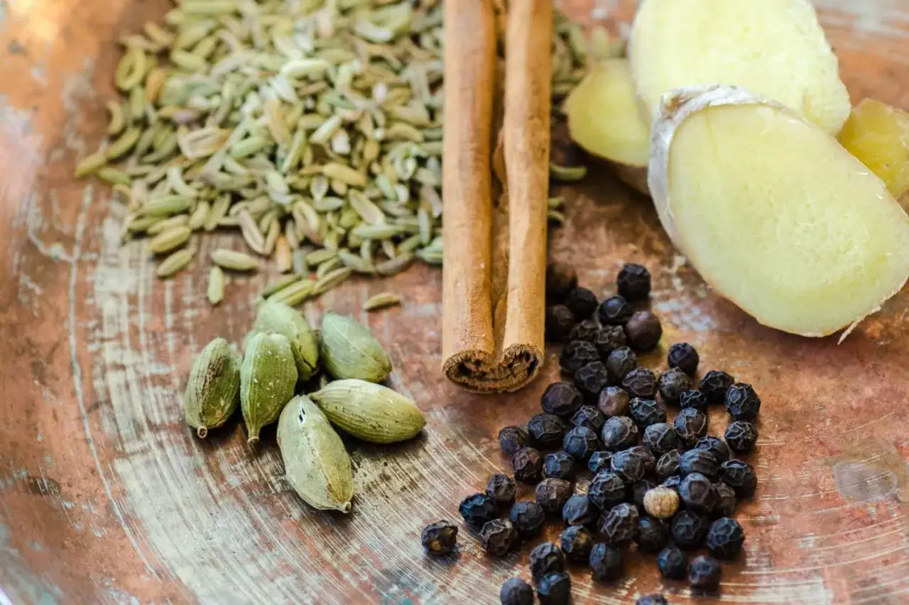 Kardemumma, kanel, f&auml;nk&aring;lsfr&ouml;n, pepparkorn och ingef&auml;ra p&aring; en koppartallrik. Ingredienserna som ger te smak.